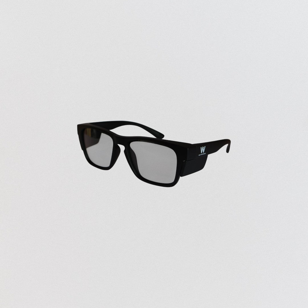 Black self-tinting safety glasses with a logo on a light gray background