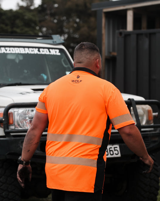 Man walking away with orange high visibility t-shirt on, WOLF workwear logo on the back of it.