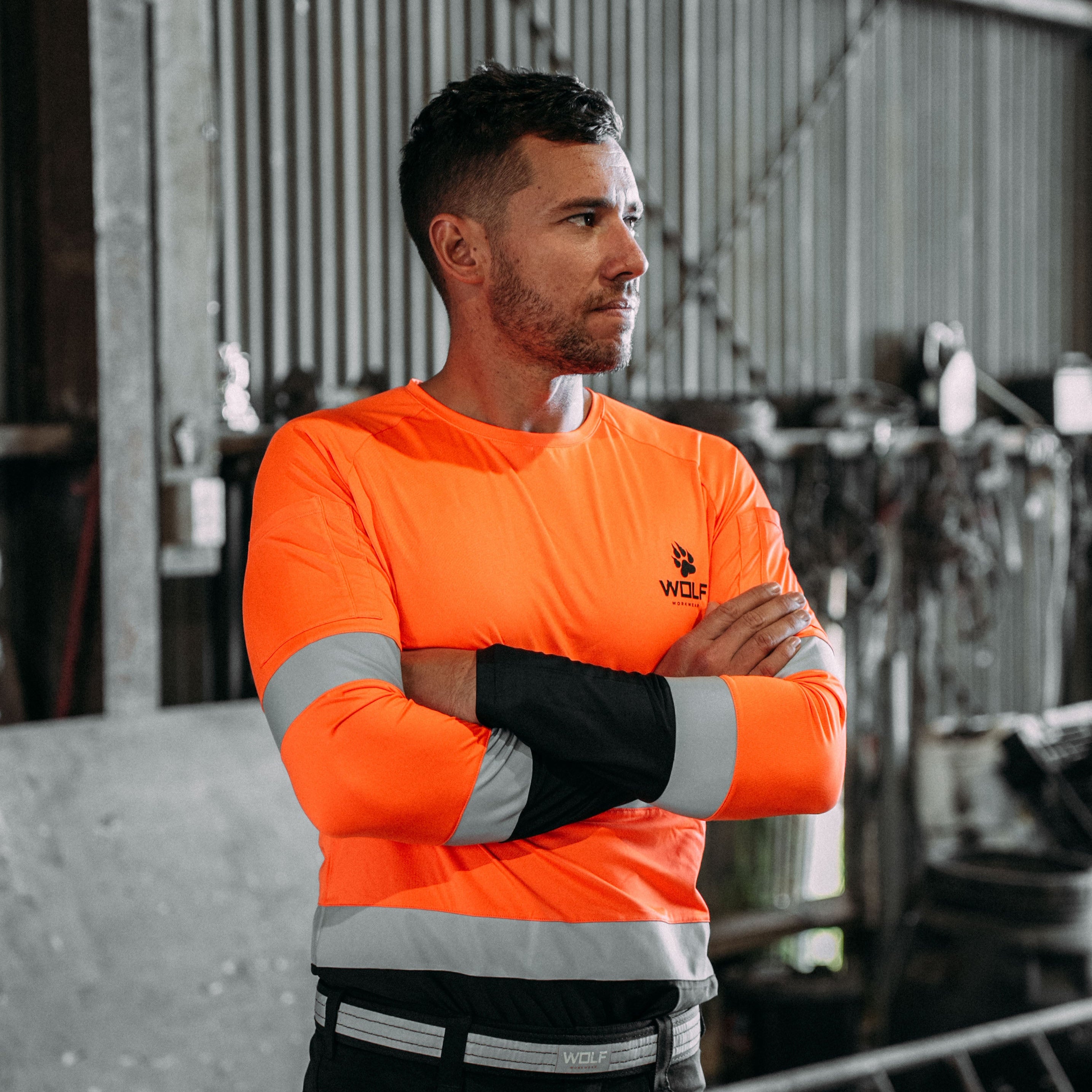 Man standing with arms crossed in high visibility long sleeve shirt