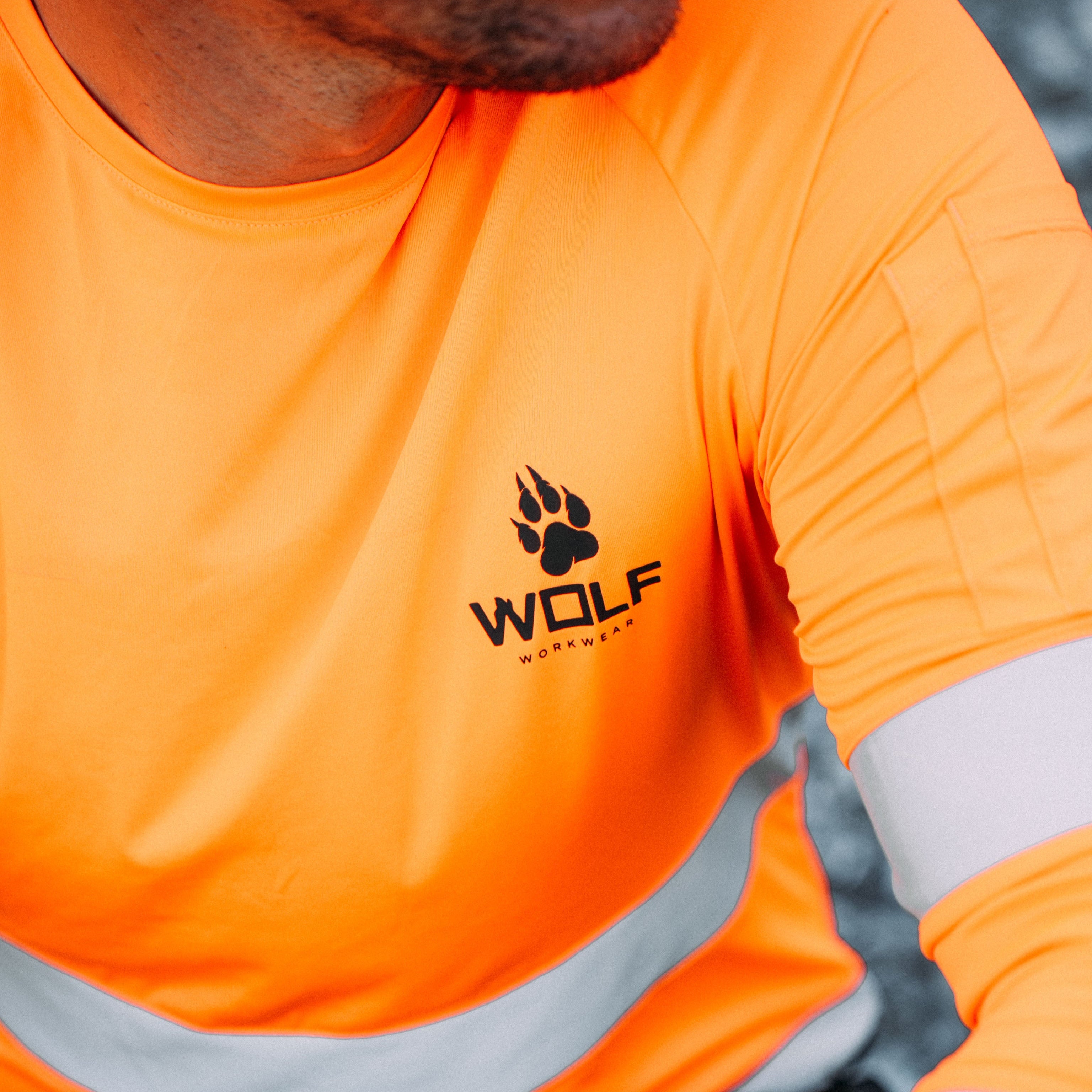 Up close photograph of a man wearing a high visibility work shirt with the Wolf Workwear logo.