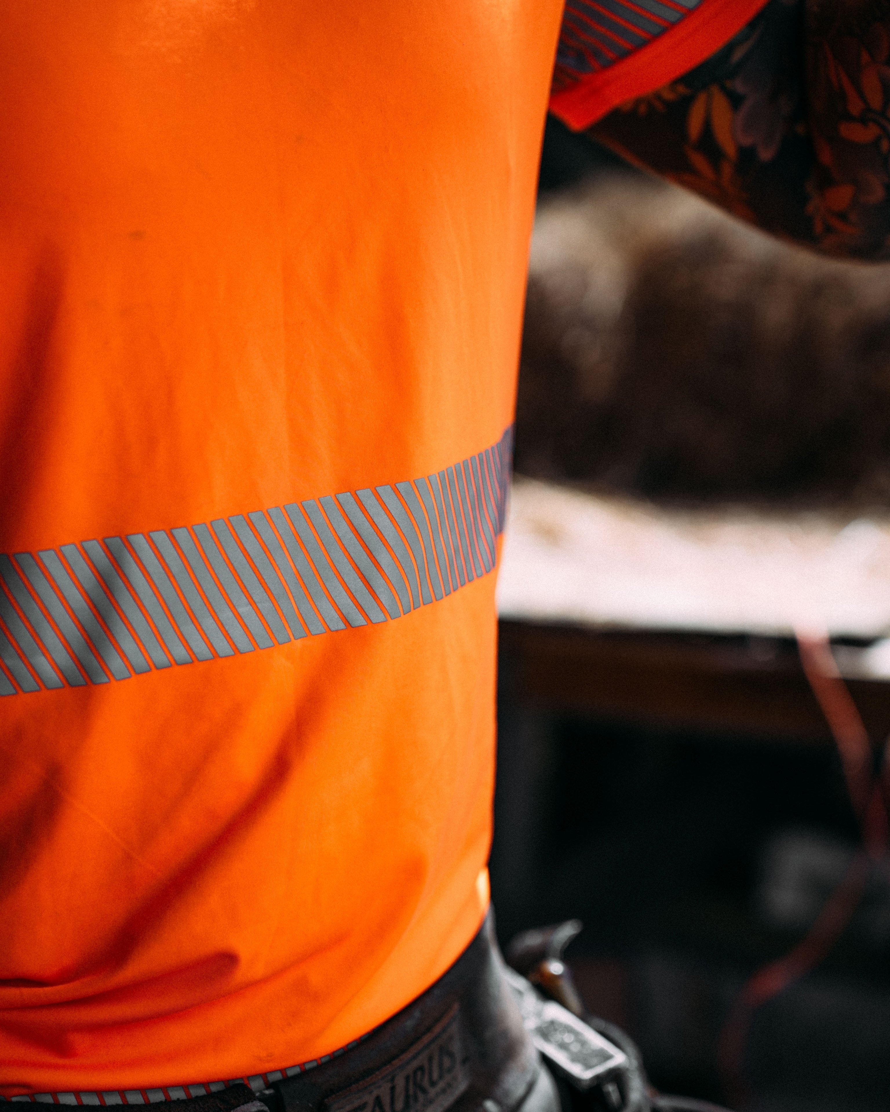 Close up of men's high visibility orange t-shirt and reflective strip