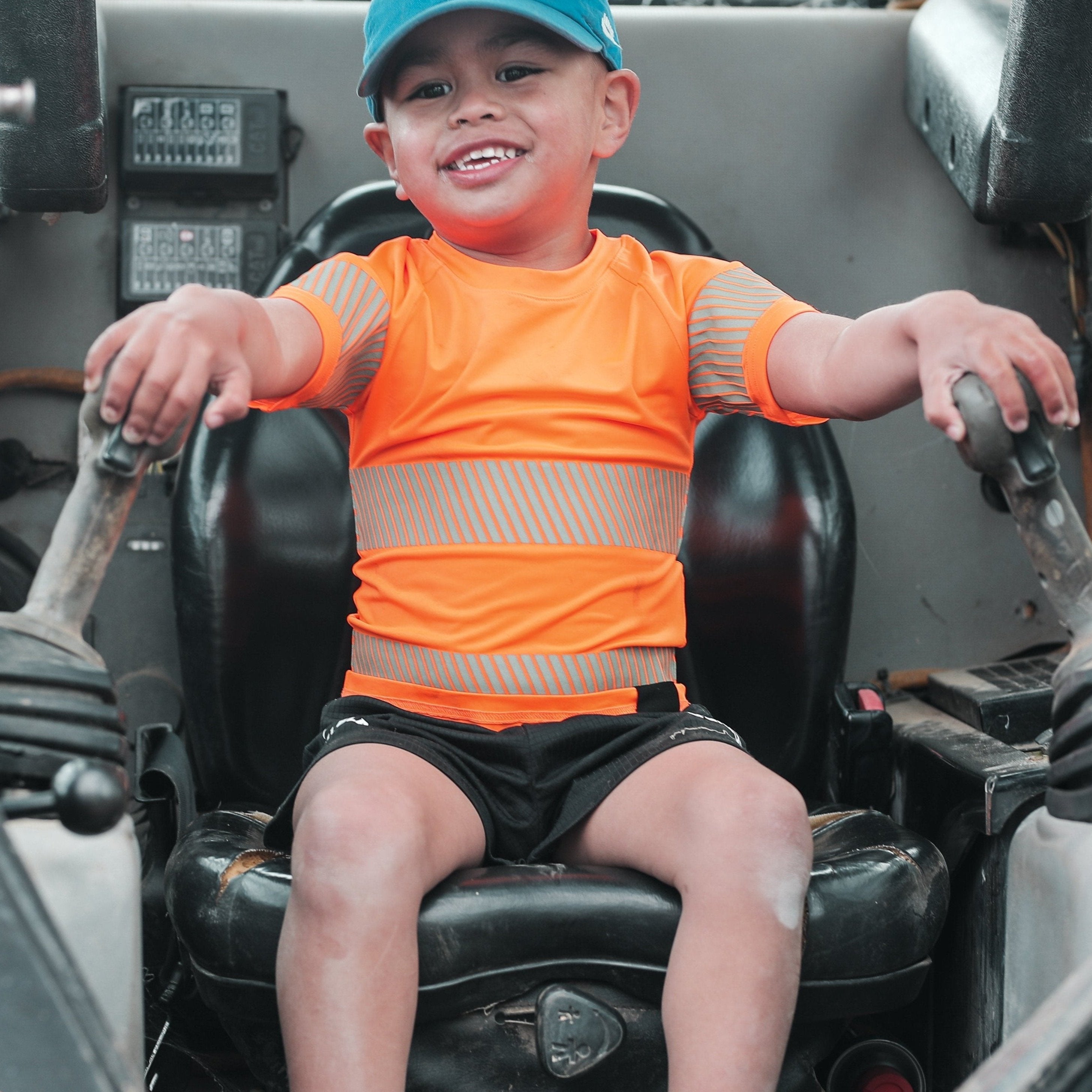 Boy in machinery wearing organge high visibility t-shirt