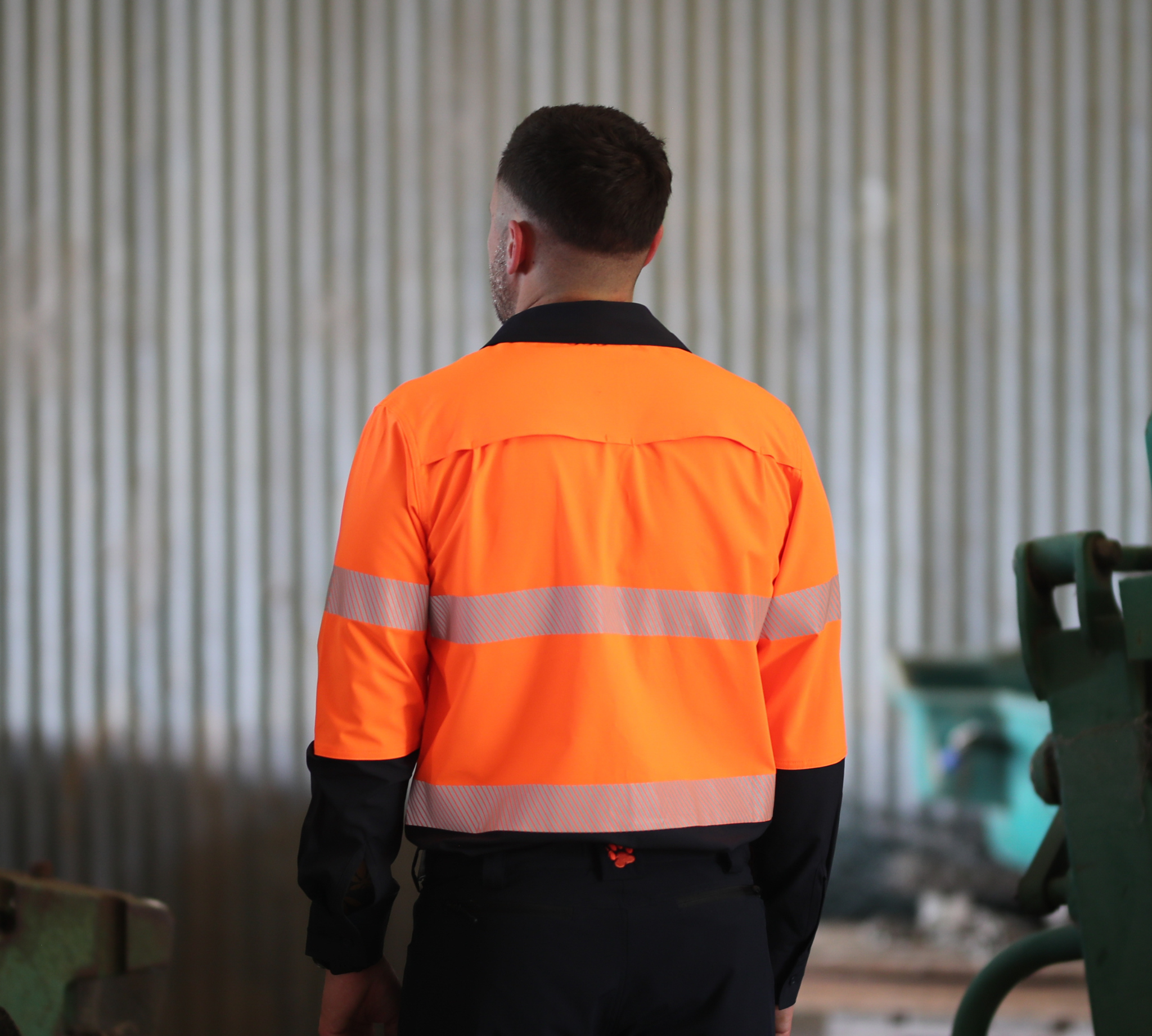 Person wearing an orange safety jacket in a workshop setting