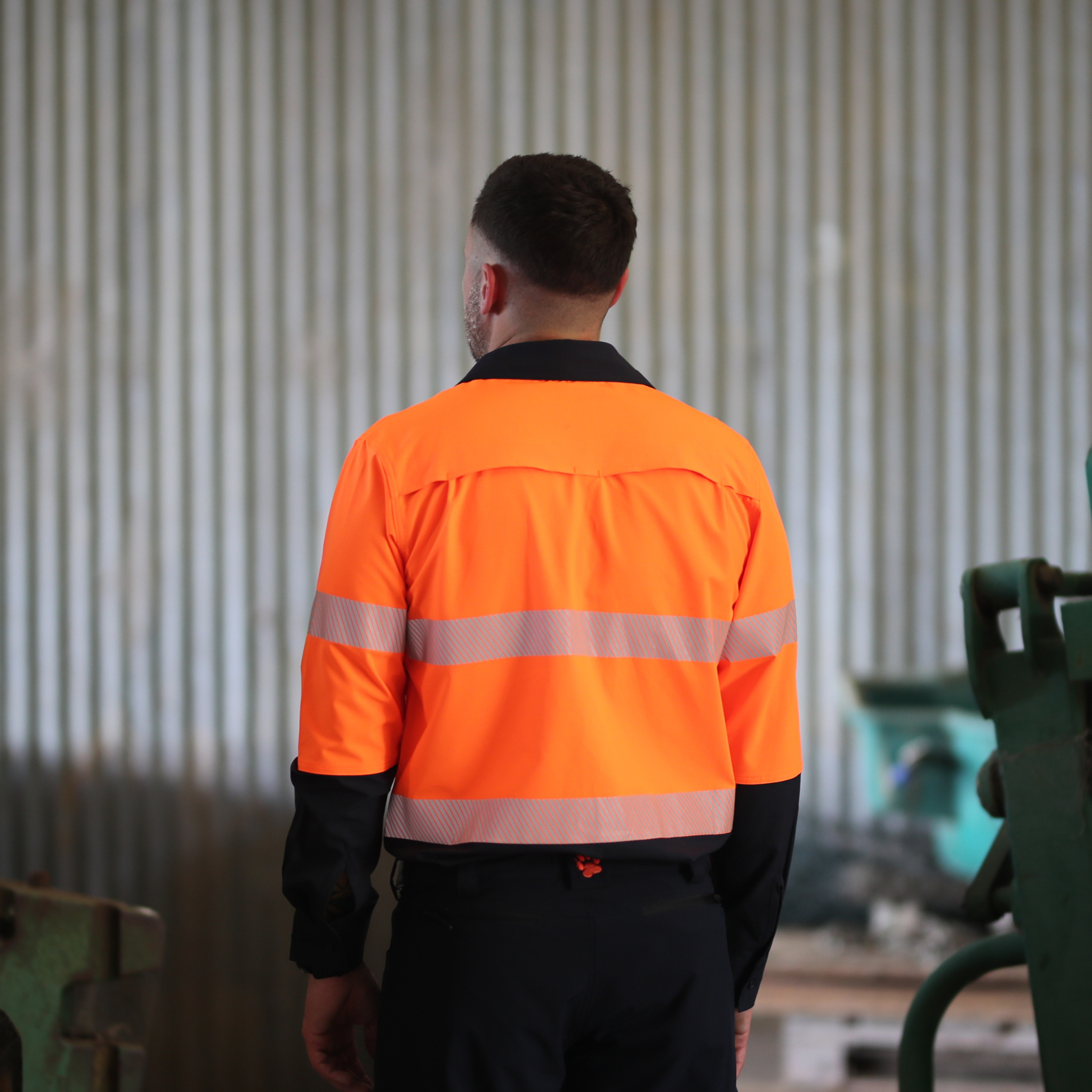 Person wearing an orange safety jacket in a workshop setting