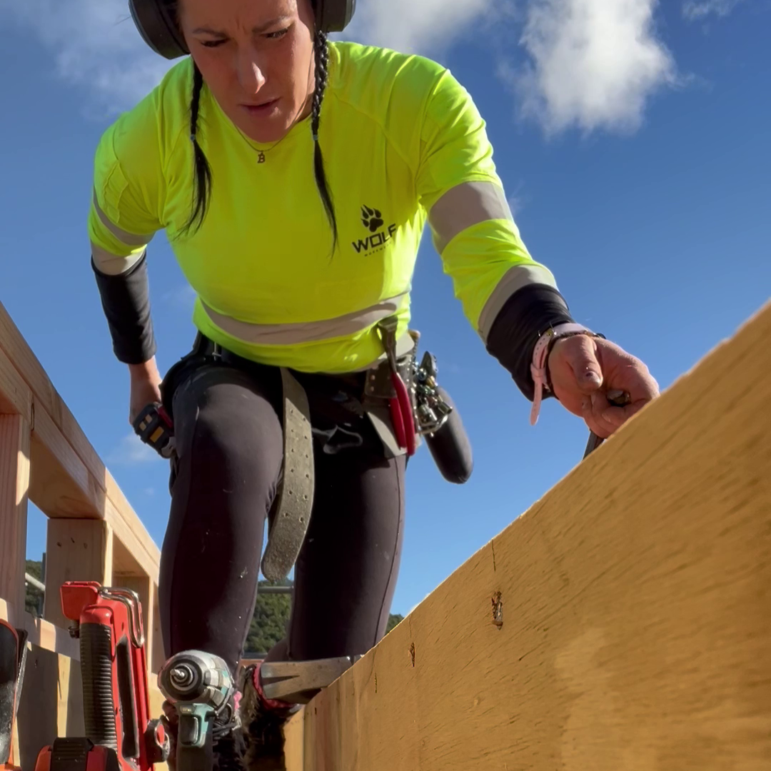Person in high-visibility safety gear working on a construction site with tools and equipment.