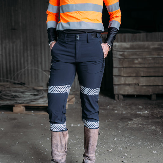 Woman standing in work shed wearing trooper work pants in navy.